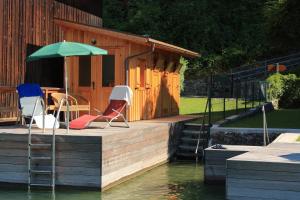 a deck with chairs and an umbrella on the water at Pension Linortner in St. Wolfgang