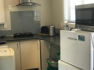 a kitchen with a white refrigerator and a microwave at Cosy Caversham Retreat in Dunedin