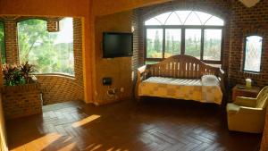 a room with a bed and a tv and windows at Castillo San Carlos Lomas de Cocoyoc con Cancha de Padel 16Huespedes in Cocoyoc