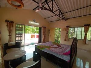 GhātgharWeekend Villa at Nature's Lap (Malshej Ghat)的一间卧室，配有一张床、一张桌子和几把椅子