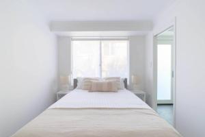 a white bedroom with a large bed and a window at Abbey House - 3BR/sleeps 8 - South Leura in Leura