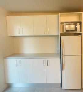 cocina con armarios blancos y nevera en Lake Munmorah Motel, en Lake Munmorah