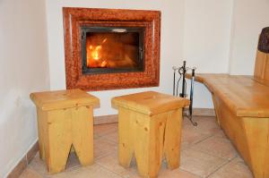 una chimenea con dos taburetes de madera frente a ella en Albergo Neni, en Brentonico