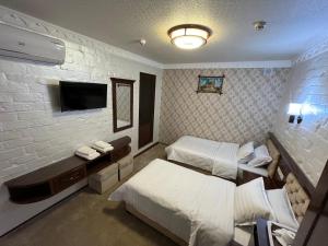 a hotel room with two beds and a television at Hotel Grand Marakand in Samarkand