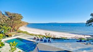 a swimming pool with chairs and a beach at Amarna Luxury Beach Resort in Nelson Bay