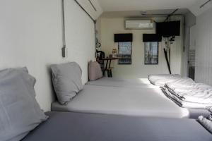 una fila de camas blancas en una habitación en Patoey House, en Chonburi
