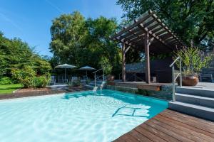 a swimming pool with a wooden deck and a pergola at Ferienhotel Haus Becker in Bad Laer