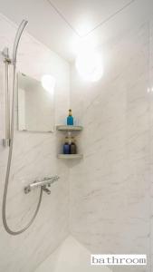 La salle de bains est pourvue d'une douche et d'un mur carrelé blanc. dans l'établissement Aparthotel Palais Royal with Parking, à Sapporo