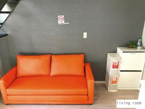 un divano arancione in una stanza con parete grigia di Aparthotel Palais Royal with Parking a Sapporo