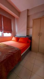 a bedroom with a bed with red sheets and a window at Apt 2 BR Sunter Park View With Pool and Netflix in Jakarta