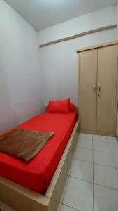 a small bedroom with a red bed and a cabinet at Apt 2 BR Sunter Park View With Pool and Netflix in Jakarta