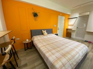 a bedroom with a bed with an orange wall at Flower House in Tainan