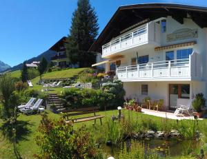 ein großes weißes Gebäude auf einem Hügel mit Garten in der Unterkunft Ferienwohnung Vier Jahreszeiten in Hirschegg