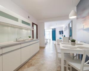 cocina con armarios blancos, mesa y comedor en Morski Anioł by Baltic Home en Świnoujście