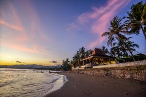 uma praia com um restaurante e palmeiras e o oceano em Bali Santi Bungalows em Candidasa
