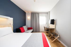 サン・クガ・デル・バリェスにあるホリデイ イン エクスプレス サン クガのベッドとデスクが備わるホテルルームです。