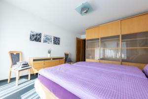 Schlafzimmer mit einem lila Bett und einem Schreibtisch in der Unterkunft Apartments Saasunia in Saas-Grund