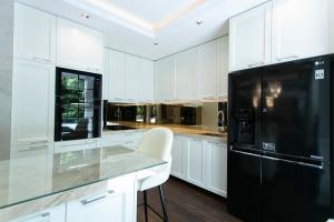 eine Küche mit weißen Schränken und einem schwarzen Kühlschrank in der Unterkunft Truth Touch of Luxury in Belgrad