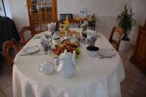 einen Tisch mit einem weißen Tischtuch mit einem Teller Essen in der Unterkunft L' ESCALE SINAGOTE Chambre d'hôtes in Séné
