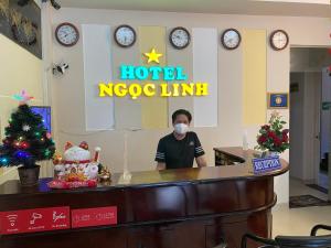 un hombre de pie en un mostrador de recepción del hotel usando una máscara en Ngoc Linh Hotel, en Ho Chi Minh