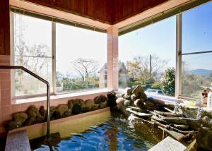 a swimming pool with a waterfall in a room with windows at Healing space tajima Shinmoe in Kirishima