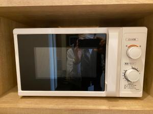 a person taking a picture of a microwave at Flexstay Inn Sakuragicho in Yokohama