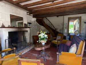 a living room with a fireplace and yellow chairs at Moulin de Battereau - Jardin & Verger - 9km d'Amboise in Saint-Martin-le-Beau