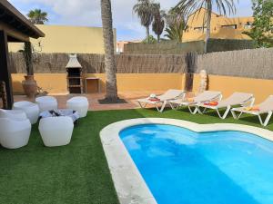 uma piscina com espreguiçadeiras, uma mesa e comodidades para churrascos em Villa Coral em Corralejo