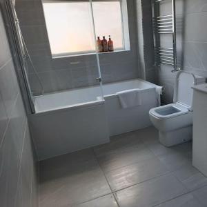 een badkamer met een bad, een toilet en een raam bij South Shield's Hidden Gem Amethyst 3 Bedroom House Sleeps 6 Guests in South Shields