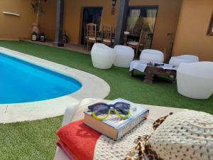 a table with a book and glasses next to a swimming pool at Villa Coral in Corralejo