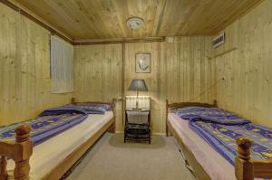 two beds in a room with wooden walls at Planinska kuća Kamin in Jahorina
