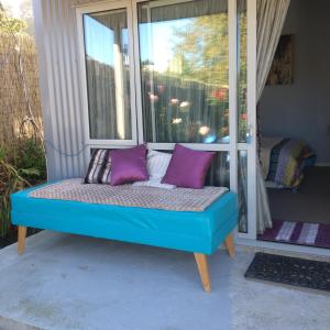 a blue bench sitting in front of a window at Cosy Caversham Retreat in Dunedin