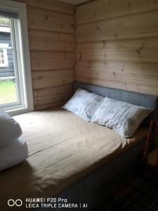 Bett in einem Blockhaus mit Fenster in der Unterkunft Lyngen ski- og fiskecamp in Lenangsøyra