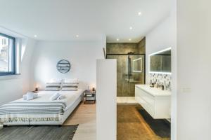 a white bedroom with a large bed and a bathroom at Sweet Inn - Rue Dansaert in Brussels