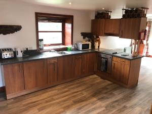 a kitchen with wooden cabinets and black counter tops at Maberry Cottage in Bargrennan