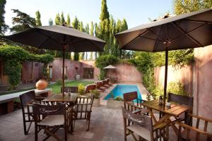 un patio con mesas y sombrillas junto a una piscina en Posada Borravino en Chacras de Coria
