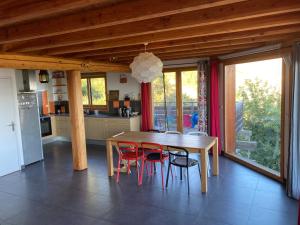 uma cozinha com uma mesa de madeira e cadeiras vermelhas em Chalet bioclimatique avec vue sur le lac de Serre Ponçon em Saint-Apollinaire