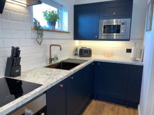 a kitchen with blue cabinets and a sink at Beechwood Nook- Crown Lodges in Crawshaw Booth
