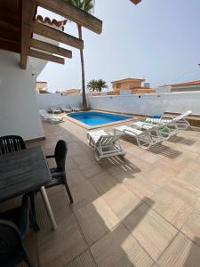 patio z leżakami i basenem w obiekcie Villa One Tenerife w mieście Costa Del Silencio