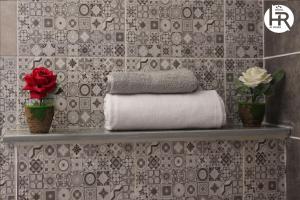 ein Badezimmer mit einem Regal mit Handtüchern und Blumen in der Unterkunft Hotel al rayan in Tataouine