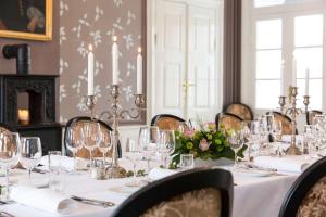 a dining room with a table with glasses and flowers at Dragsholm Slot in Hørve