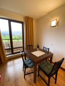 a dining room with a table and chairs and a large window at Sunny duplex with spectacular view in Terra Complex in Razlog