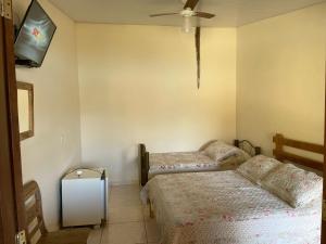 1 Schlafzimmer mit 2 Betten und einem Flachbild-TV in der Unterkunft Pousada e Restaurante do Porto in São João Batista do Glória