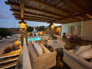 patio con sedie, tavolo e piscina di Kalafatis Private Villa Mykonos a Kalafatis