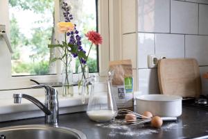 um balcão de cozinha com um lavatório com leite e flores em Natuurhuisje ‘t Oetzicht em Markelo