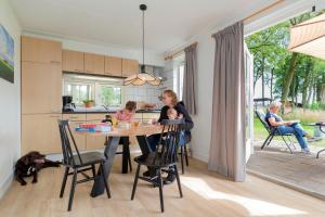 馬爾克洛的住宿－Natuurhuisje ‘t Oetzicht，坐在厨房桌子上的女人和两个孩子