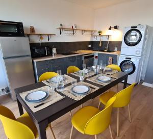 a dining room table with yellow chairs and a kitchen at Appartement Mâcon Centre T4 - 100m2 in Mâcon