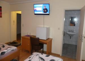 a room with a bed and a desk with a television on the wall at Hotel Akropolis in Herford