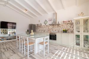 a kitchen with white cabinets and a island with stools at Villa Daniela - Private Pool and Serene Location, by ZanteWize in Koríthion
