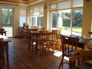 a dining room with tables and chairs and windows at Hy Breasal B&B in Achill Sound